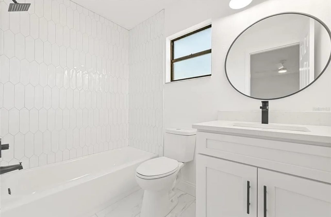 Small bathroom with white hexagon tile and round mirror