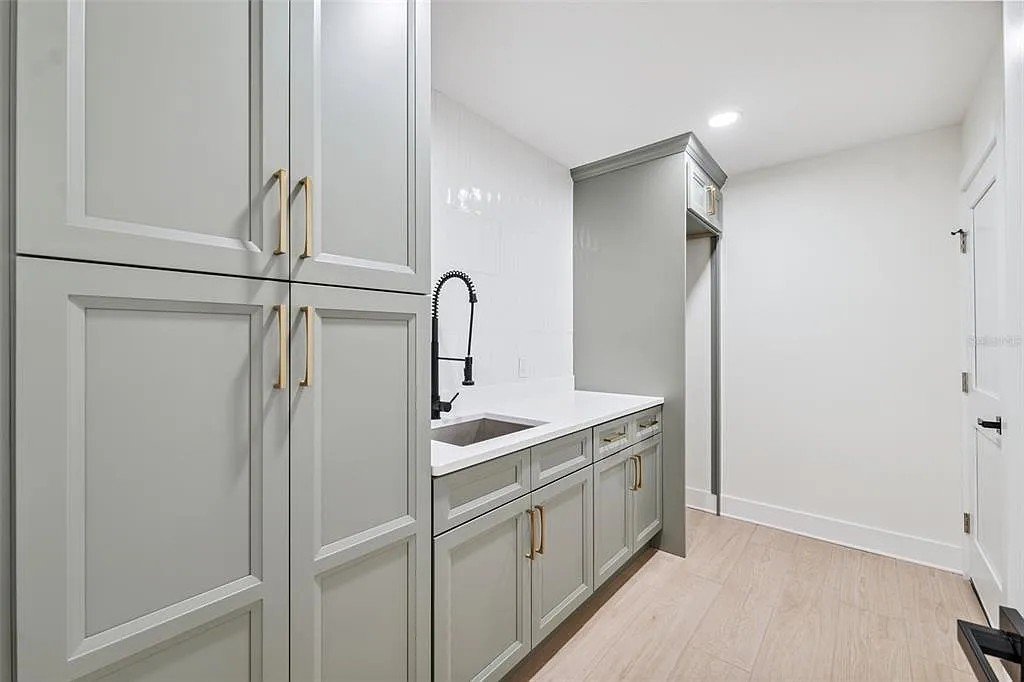 Laundry room cabinetry with dark cabinets, quartz countertop and sink Holiday FL