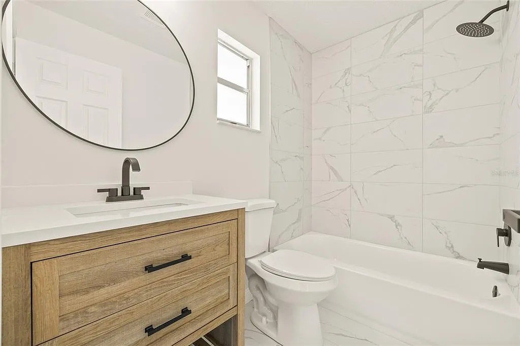 Small bathroom remodel with wood vanity marble tile Holiday FL